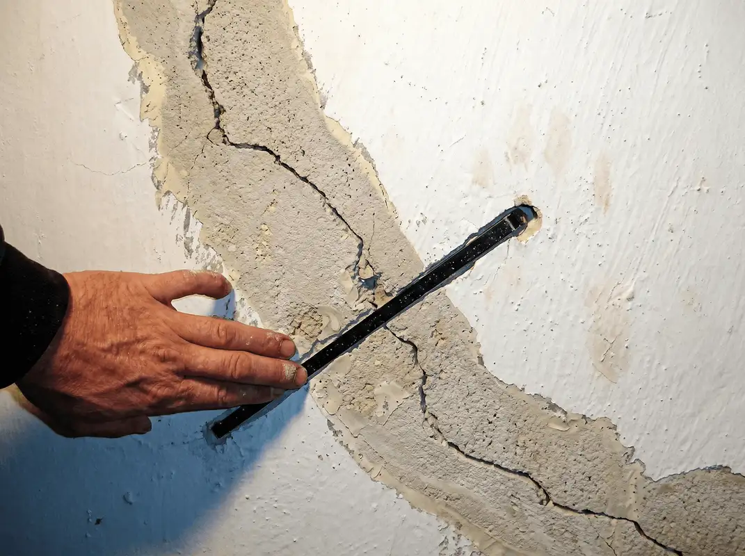 A wall with a large crack is being inspected by a professional in Hialeah, FL
